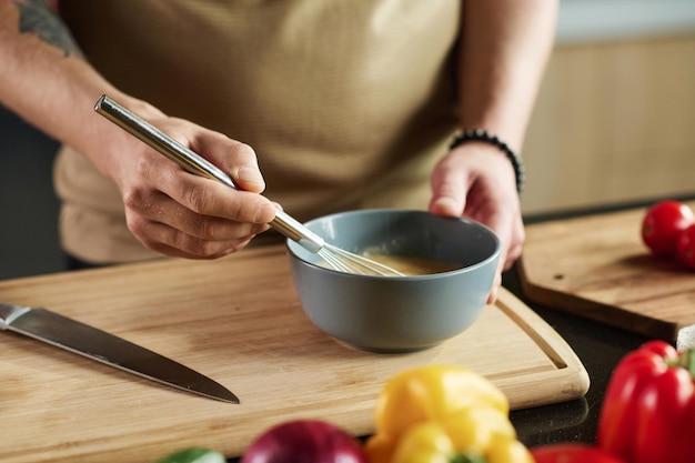 Dłoń trzymająca łyżkę nad garnkiem